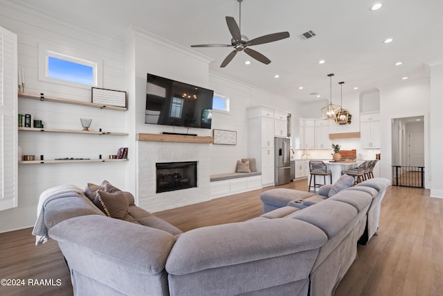 living room with crown molding, hardwood / wood-style flooring, and ceiling fan with notable chandelier