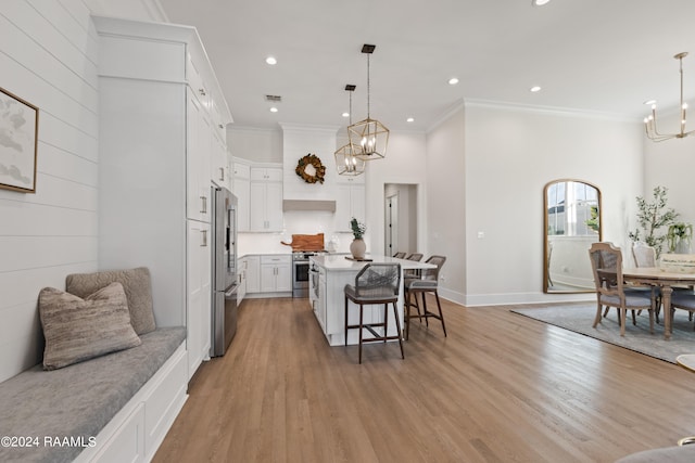 kitchen featuring stainless steel appliances, a center island, a kitchen bar, white cabinets, and light hardwood / wood-style floors