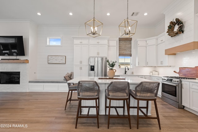 kitchen with appliances with stainless steel finishes, a kitchen island, white cabinetry, pendant lighting, and a breakfast bar area