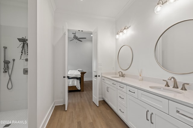 bathroom featuring a tile shower, hardwood / wood-style flooring, ornamental molding, and vanity