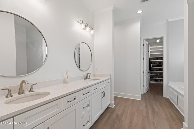 bathroom with vanity, ornamental molding, hardwood / wood-style flooring, and a tub to relax in