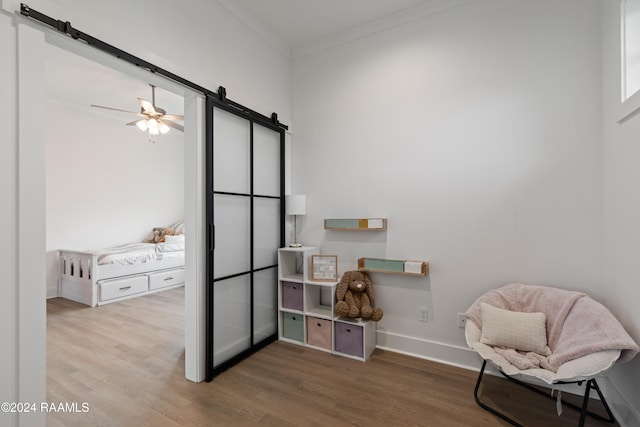 living area featuring ornamental molding, a barn door, wood-type flooring, and ceiling fan