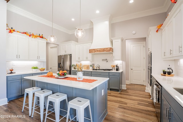 kitchen featuring custom exhaust hood, white cabinets, a kitchen island, appliances with stainless steel finishes, and dark wood-type flooring