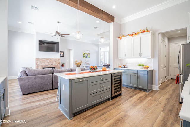 kitchen with wine cooler, a kitchen island, white cabinets, and light wood-type flooring