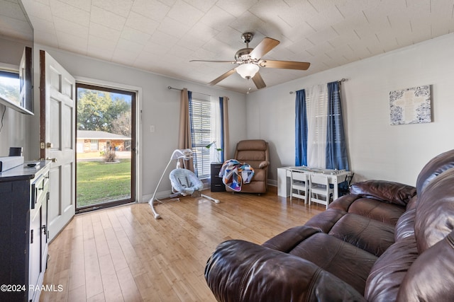 living room with ornamental molding, light wood-type flooring, and ceiling fan