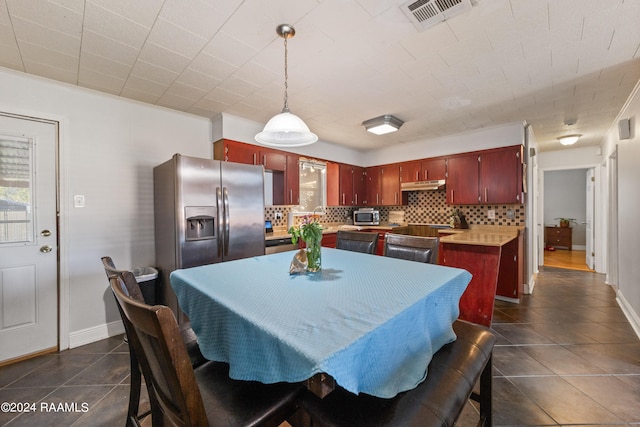 kitchen with dark tile patterned flooring, wood counters, decorative light fixtures, appliances with stainless steel finishes, and tasteful backsplash