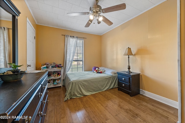 bedroom featuring ceiling fan, crown molding, and wood-type flooring