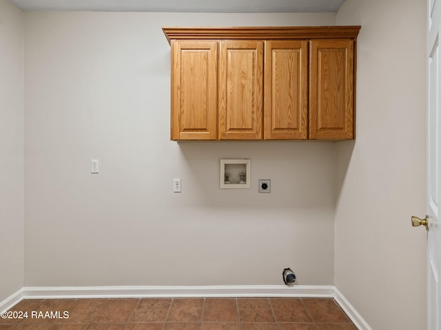 laundry area with hookup for an electric dryer, hookup for a washing machine, cabinets, and dark tile patterned flooring