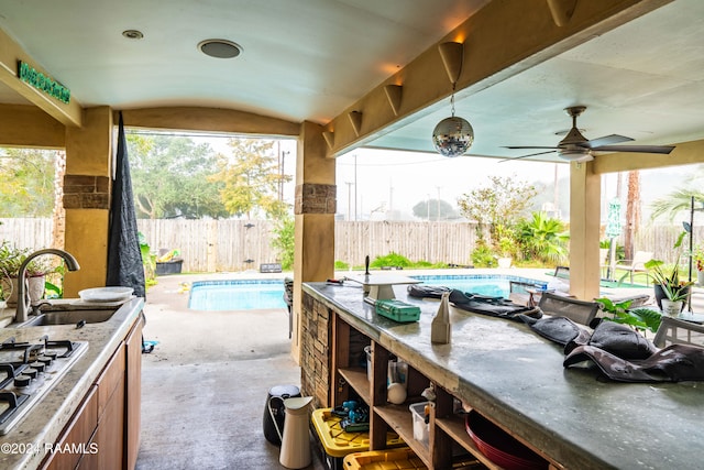 view of patio with ceiling fan, a fenced in pool, and sink