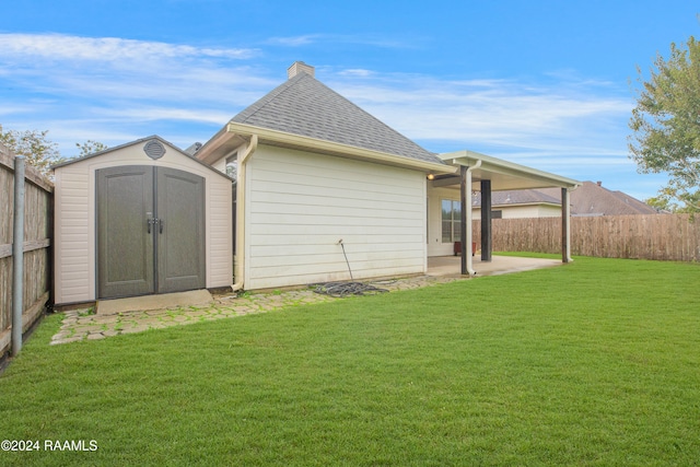 back of property with a patio, a lawn, and a shed