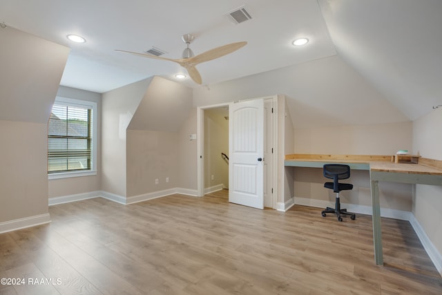 unfurnished office featuring built in desk, ceiling fan, light wood-type flooring, and vaulted ceiling