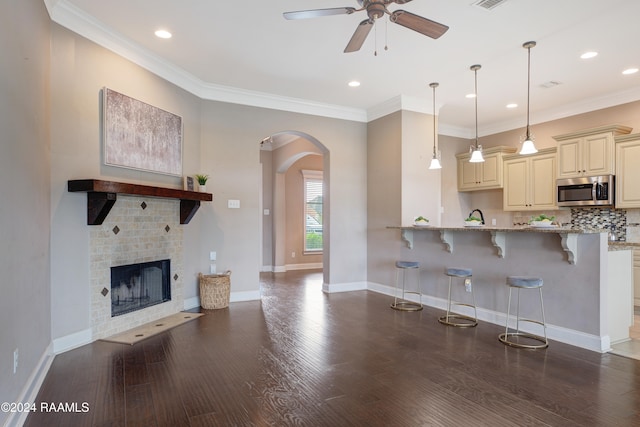 kitchen featuring light stone counters, dark wood-type flooring, cream cabinetry, and a breakfast bar