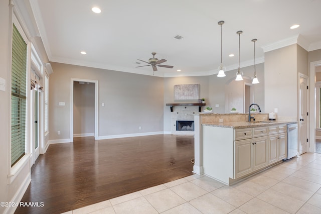 kitchen featuring ornamental molding, light wood-type flooring, light stone countertops, hanging light fixtures, and stainless steel dishwasher