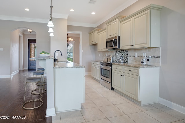 kitchen featuring appliances with stainless steel finishes, sink, decorative light fixtures, and light stone countertops