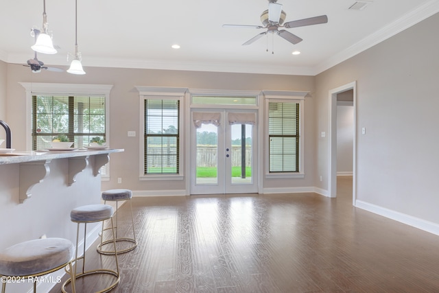 interior space featuring pendant lighting, a kitchen breakfast bar, dark wood-type flooring, and crown molding