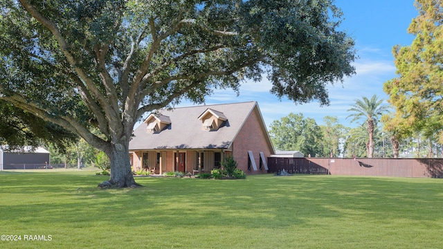 cape cod home with brick siding, fence, and a front lawn
