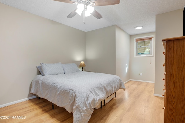 bedroom featuring light wood-style floors, a textured ceiling, baseboards, and ceiling fan