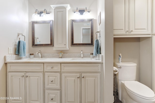 bathroom featuring double vanity, a sink, and toilet