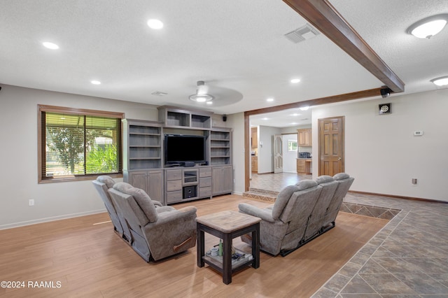 living room featuring baseboards, ceiling fan, a textured ceiling, and visible vents