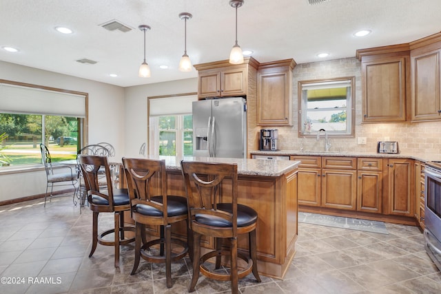 kitchen featuring brown cabinets, appliances with stainless steel finishes, a healthy amount of sunlight, and a sink