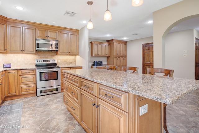 kitchen with a kitchen breakfast bar, backsplash, visible vents, arched walkways, and stainless steel appliances
