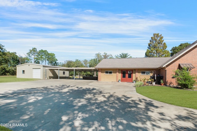 view of front facade featuring brick siding, a front lawn, an outbuilding, and concrete driveway