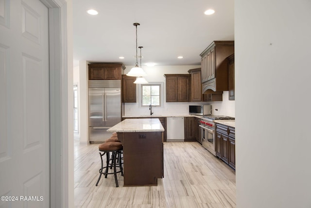 kitchen with a center island, hanging light fixtures, dark brown cabinets, and premium appliances