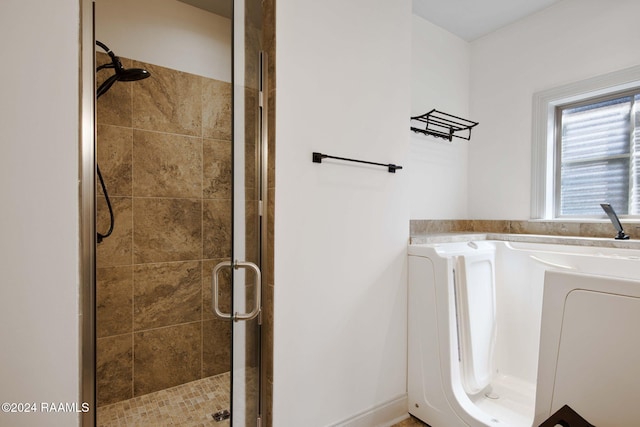 bathroom featuring washer / clothes dryer and separate shower and tub