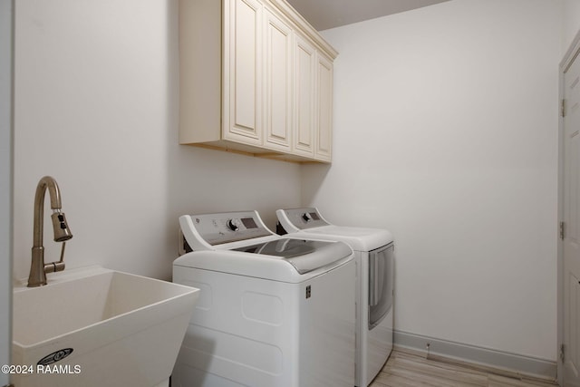 washroom with cabinets, sink, washer and clothes dryer, and light wood-type flooring