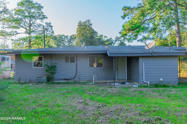 rear view of property with central AC and a lawn