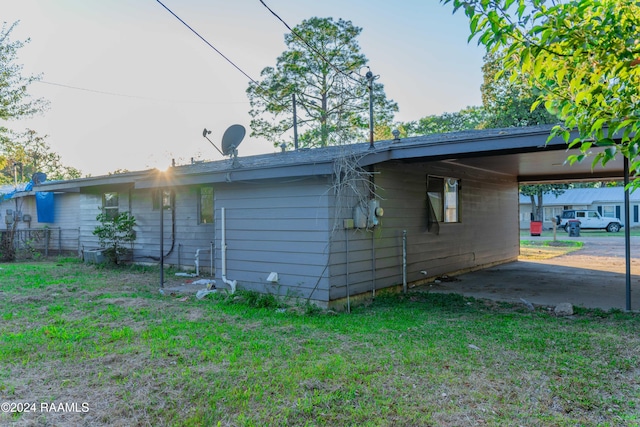 rear view of property featuring a carport and a lawn