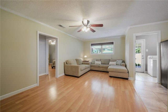 unfurnished living room with washer / dryer, a textured ceiling, light wood finished floors, and crown molding