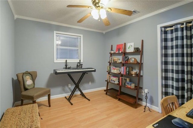 interior space with baseboards, light wood-style flooring, ceiling fan, ornamental molding, and a textured ceiling