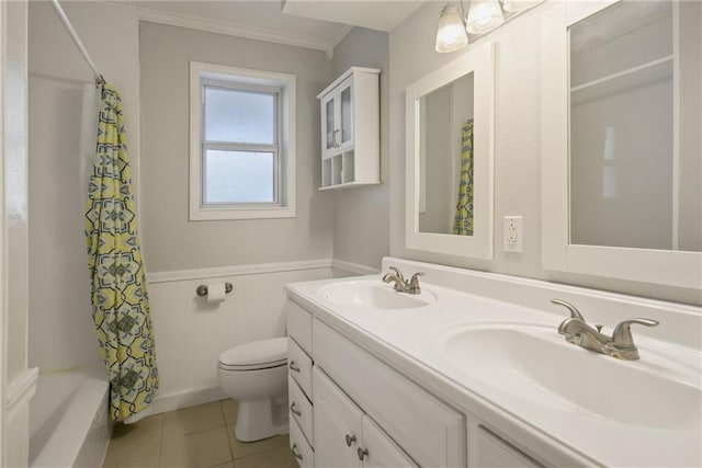 bathroom featuring toilet, tile patterned flooring, a sink, and wainscoting