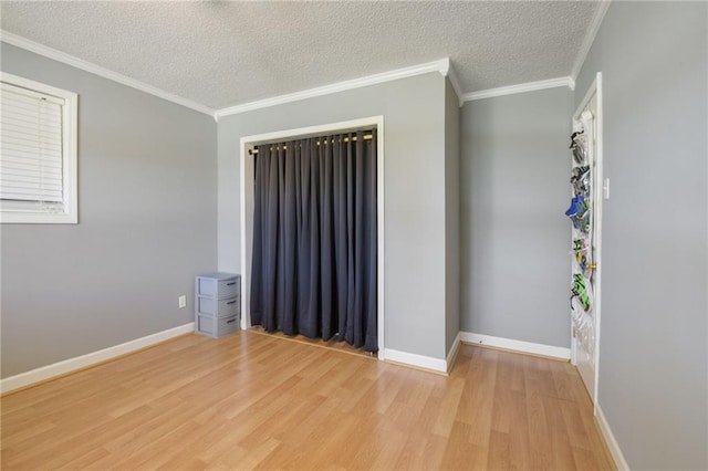 unfurnished room featuring baseboards, a textured ceiling, ornamental molding, and wood finished floors