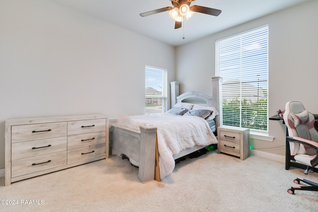 bedroom featuring light carpet, multiple windows, and ceiling fan