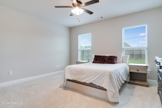 carpeted bedroom featuring multiple windows and ceiling fan