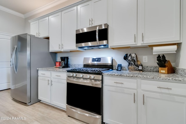 kitchen featuring crown molding, light wood-type flooring, appliances with stainless steel finishes, light stone countertops, and white cabinets