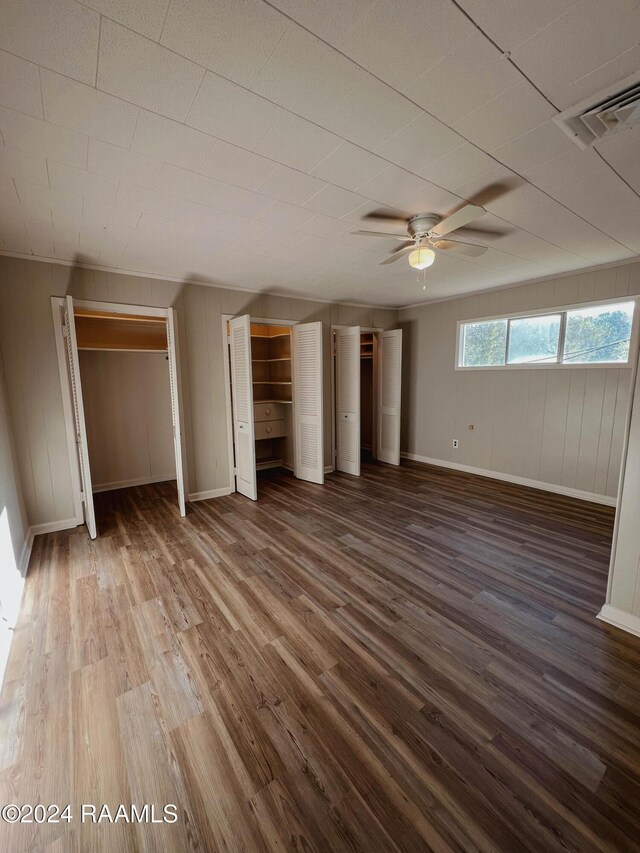 404 W Hickory St, Ville Platte, LA 70586 - unfurnished bedroom with wood finished floors, baseboards, two closets, and wooden walls