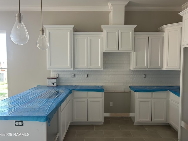 kitchen featuring pendant lighting, dark tile patterned floors, white cabinetry, tasteful backsplash, and ornamental molding