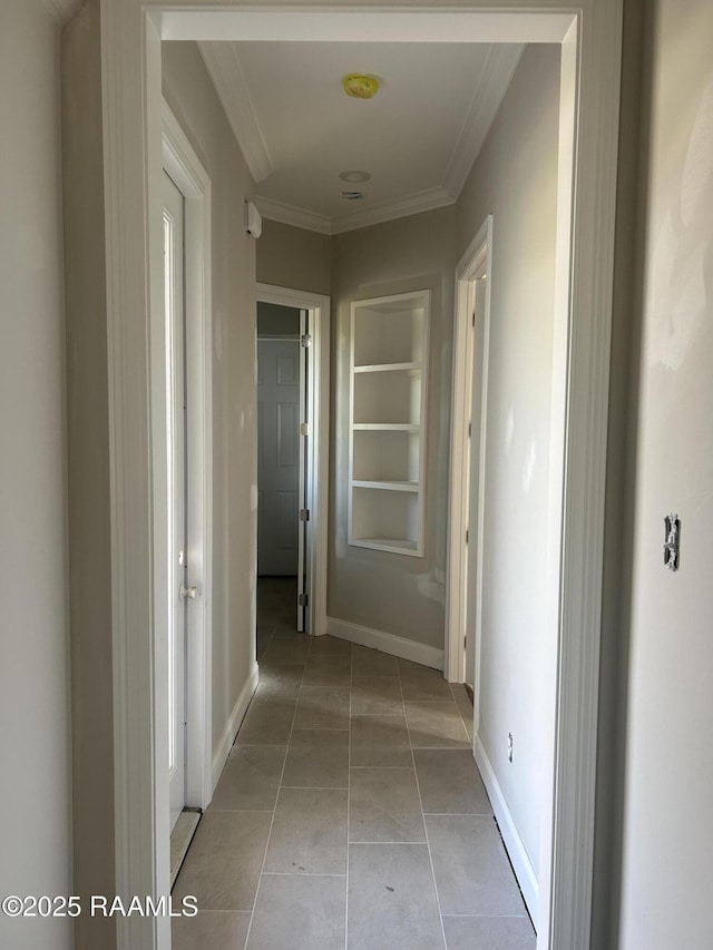 hallway with built in shelves, crown molding, and light tile patterned floors