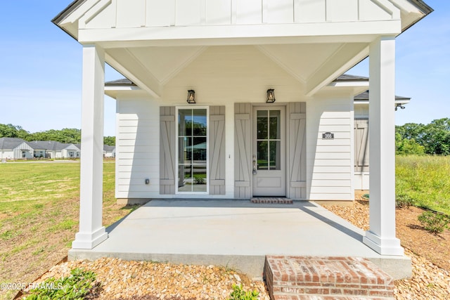 366 W Broussard Rd, Lafayette, LA 70506 - view of exterior entry with board and batten siding, a porch, and a lawn