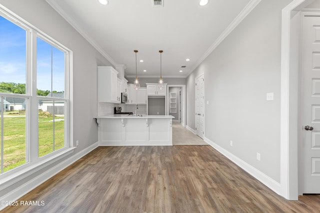 366 W Broussard Rd, Lafayette, LA 70506 - kitchen featuring stainless steel microwave, healthy amount of natural light, a peninsula, wood finished floors, and crown molding