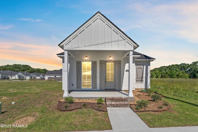 366 W Broussard Rd, Lafayette, LA 70506 - view of front of home with board and batten siding, covered porch, and a yard