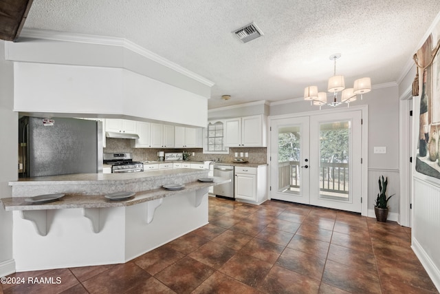 kitchen with decorative backsplash, a breakfast bar, white cabinets, decorative light fixtures, and appliances with stainless steel finishes