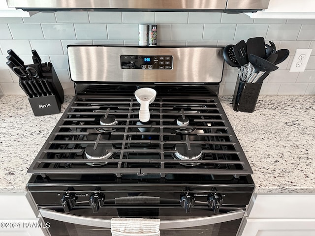 details featuring white cabinetry, stainless steel gas range oven, and tasteful backsplash