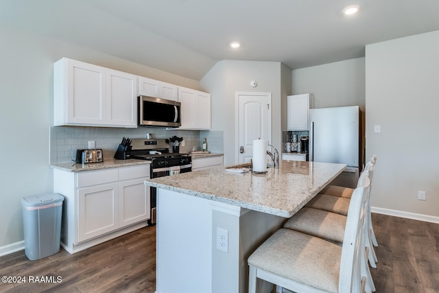 kitchen featuring a breakfast bar, white cabinets, a kitchen island with sink, and stainless steel appliances