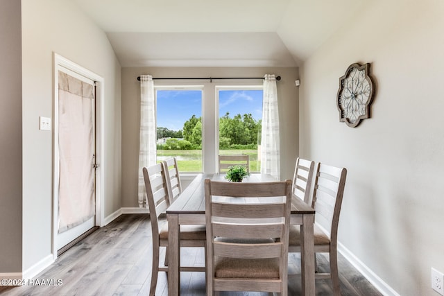 dining space featuring light wood-type flooring and vaulted ceiling