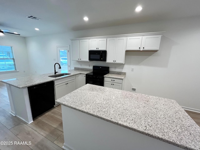 kitchen featuring white cabinets, a center island, sink, and black appliances