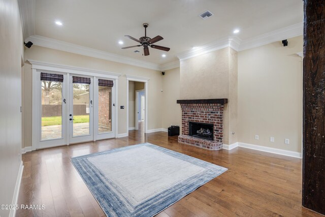 living room featuring french doors, wood-type flooring, ornamental molding, ceiling fan, and a fireplace